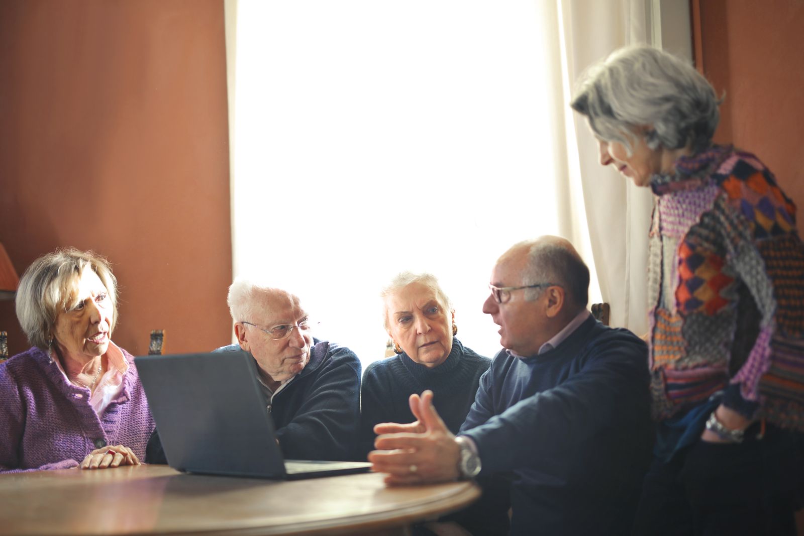 Ältere Familienangehörige sitzen gemeinsam am Tisch und besprechen Pflegefragen